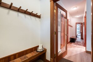 A hallway with a wooden bench, a coat rack, and a door leading to another room. - Central location spacious 2 BDR | BBQ | Pet friendly | Free parking (Whistler)