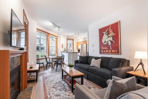 A modern living room with a sofa, armchairs, a coffee table, and a dining area with chairs and a table. - Central location spacious 2 BDR | BBQ | Pet friendly | Free parking (Whistler)