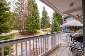 A balcony with a view of a driveway and trees, a barbecue grill, and outdoor furniture. - Central location spacious 2 BDR | BBQ | Pet friendly | Free parking (Whistler)