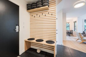 A modern interior with a wooden slatted wall, a bench with circular seats, and a door with a key lock. - Gorgeous 2+Loft | Creekside | Free Parking (Whistler)