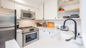 Eine moderne Küche mit Edelstahlgeräten, weißen Schränken und einem eingebauten Backofen.