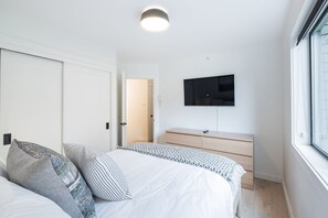 A bedroom with a bed, bedside tables, a wardrobe, a television, and a window. - Gorgeous 2+Loft | Creekside | Free Parking (Whistler)