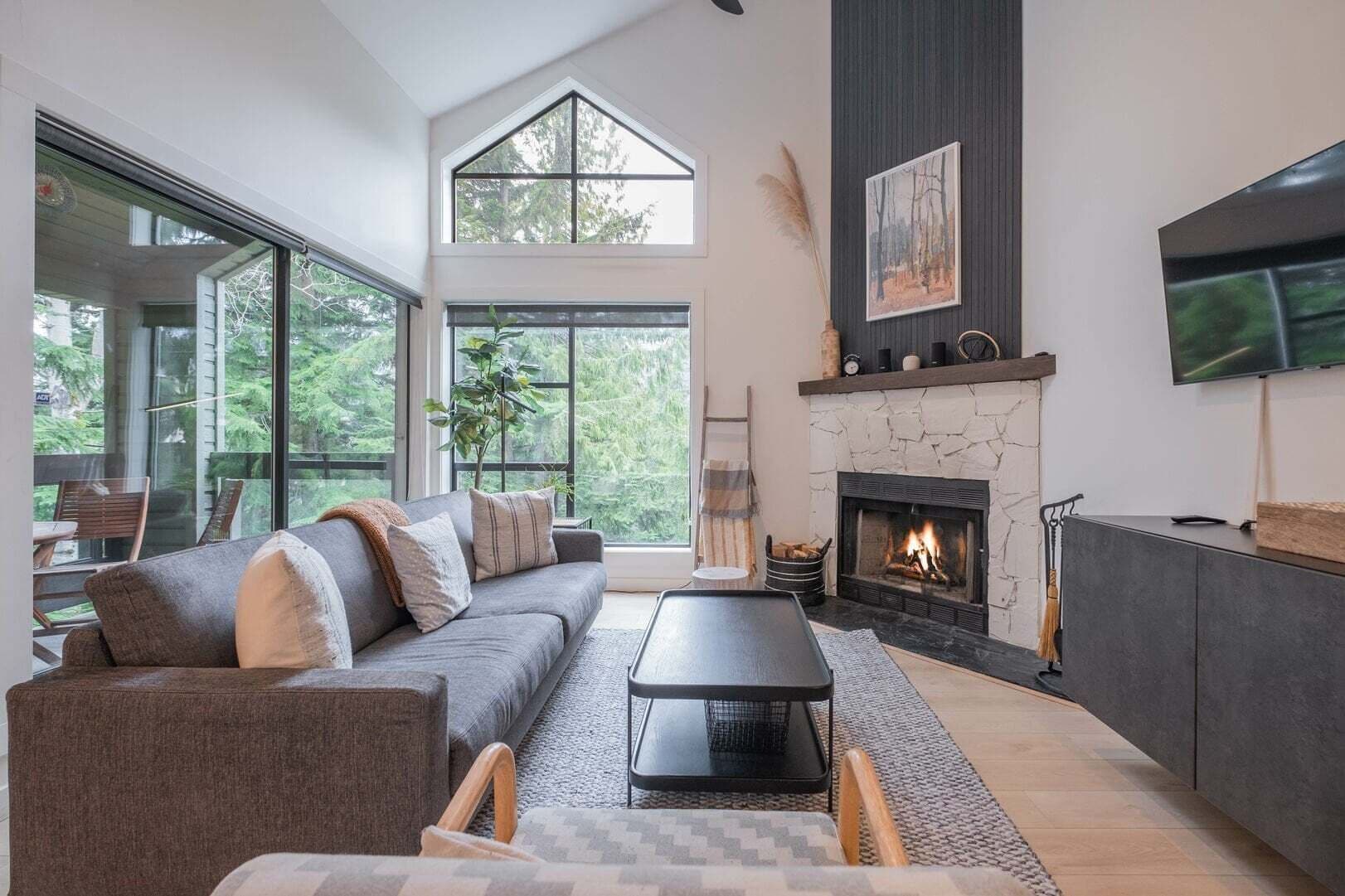A modern living room with a fireplace, a sofa, a coffee table, and a TV mounted on the wall.