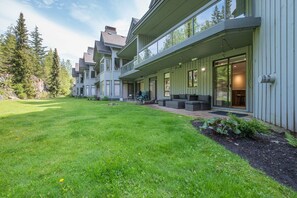 A modern multi-story house with a covered patio and a well-maintained lawn.