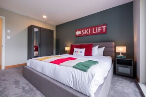 Een moderne hotelkamer met een groot bed, een bord met ski-liftaanduiding aan de muur en een grijs hoofdeinde.