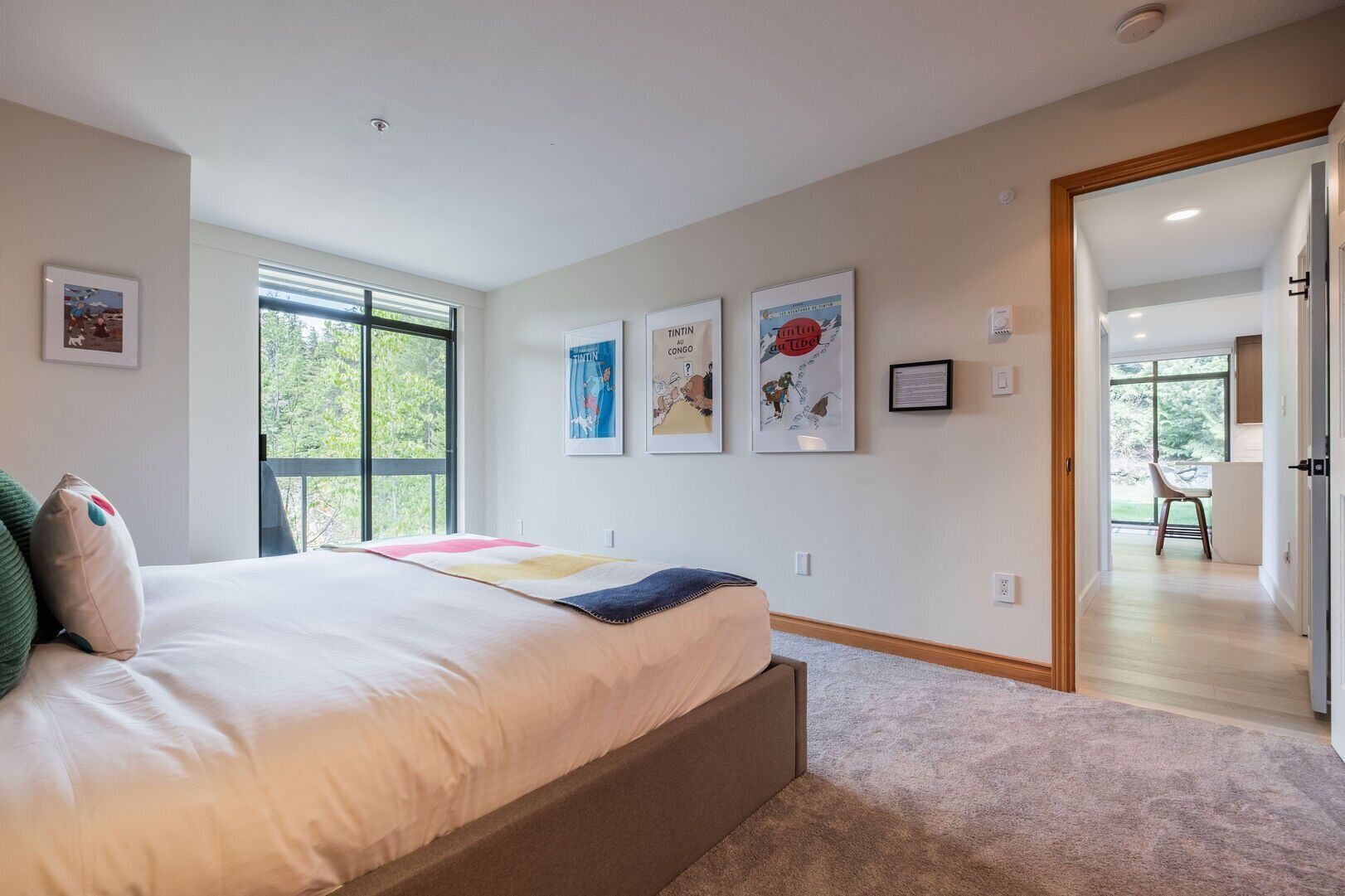Een slaapkamer met een groot bed, een raam en een deur naar een balkon.