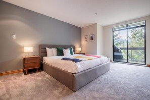 Een slaapkamer met een bed, nachtkastjes, een raam met uitzicht en een deur.