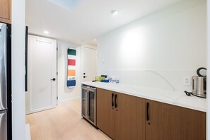 Een moderne keuken met een vaatwasser, een waterkoker en een aanrecht met diverse spullen.