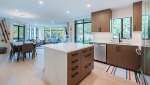 Une cuisine moderne avec des meubles en bois, un îlot central et un coin repas comprenant un canapé et une table.