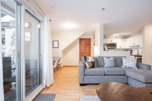 En moderne stue med en grå sofa, et træbord og et spiseområde med stole.