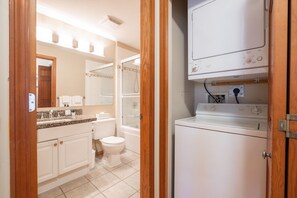 A compact bathroom with a toilet, sink, and a washing machine. - Private Hot Tub | Pets | Free Parking | Location! (Whistler)
