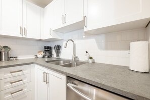 A modern kitchen with white cabinets, a double sink, and stainless steel appliances. - Private Hot Tub | Pets | Free Parking | Location! (Whistler)