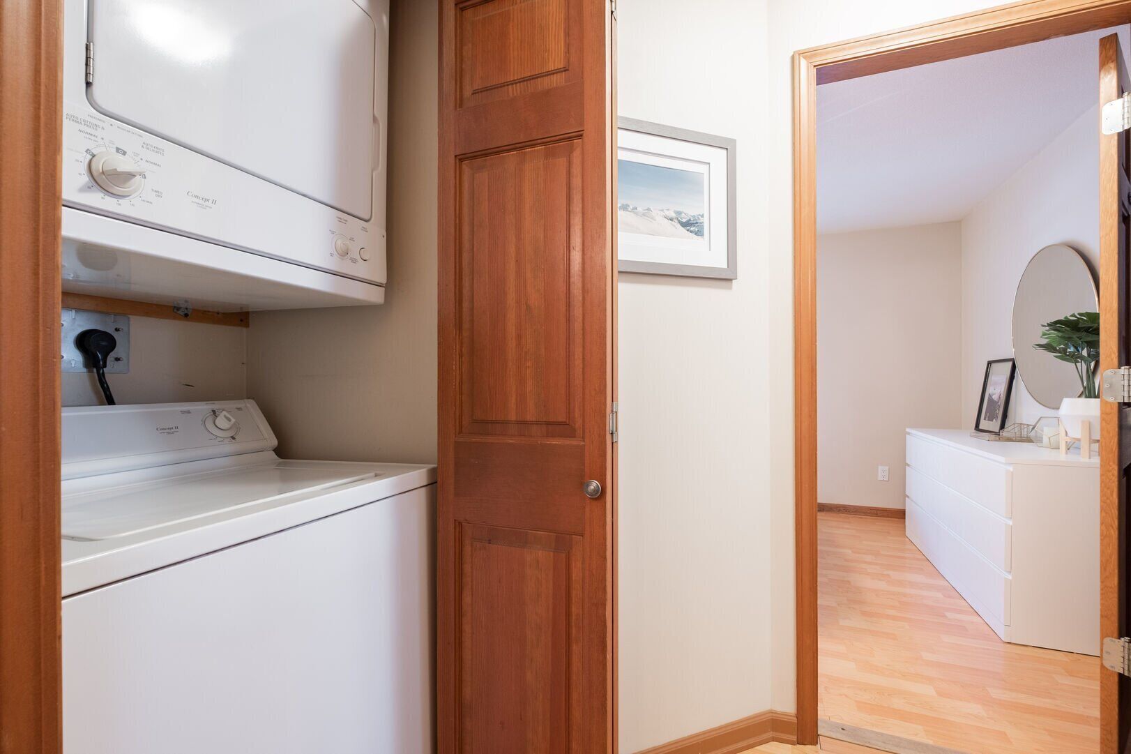 A laundry area with a washing machine, a wooden door, and a framed picture on the wall.