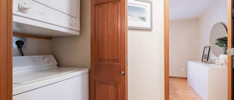 A laundry area with a washing machine, a wooden door, and a framed picture on the wall.