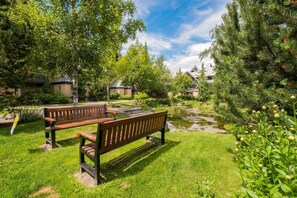 A park with two wooden benches, a pond, and surrounding greenery. - Private Hot Tub | Pets | Free Parking | Location! (Whistler)