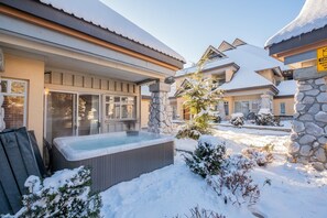 A residential area with a hot tub, stone pillars, and snow-covered surroundings. - Private Hot Tub | Pets | Free Parking | Location! (Whistler)