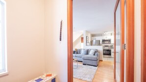 A hallway leading to a living area with a sofa, a small table, and a kitchen in the background. - Private Hot Tub | Pets | Free Parking | Location! (Whistler)