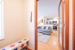 A hallway leading to a living area with a sofa, a small table, and a kitchen in the background. - Private Hot Tub | Pets | Free Parking | Location! (Whistler)