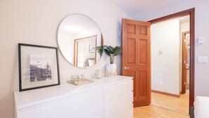 A room with a white dresser, a round mirror, a framed picture, and a wooden door. - Private Hot Tub | Pets | Free Parking | Location! (Whistler)