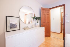 A room with a white dresser, a round mirror, a framed picture, and a wooden door. - Private Hot Tub | Pets | Free Parking | Location! (Whistler)