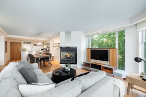 Ein modernes Wohnzimmer mit Kamin, Fernseher und Essbereich.