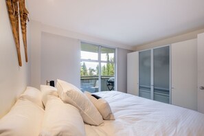 Ein Schlafzimmer mit einem großen Bett, einem Kleiderschrank und einem Fenster mit Blick auf Bäume.