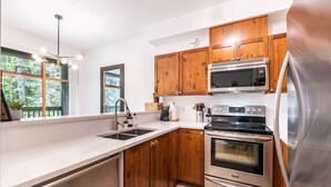 A modern kitchen with wooden cabinets, stainless steel appliances, and a large window. - Perfect location | Free Parking | Pool & Hot Tub (Whistler)