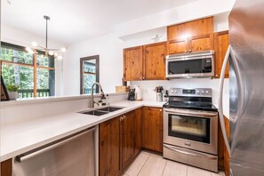 Eine moderne Küche mit Holzschränken, Edelstahlgeräten und einem großen Fenster.