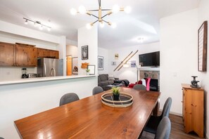 Eine moderne Küche mit Holzschränken, einem eingebauten Kühlschrank sowie einem Essbereich mit Holztisch und Stühlen.