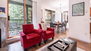 A spacious living area with a fireplace, a dining table, and a red armchair. - Perfect location | Free Parking | Pool & Hot Tub (Whistler)