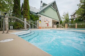 Ein Schwimmbecken mit einer Metalltreppe, die zu einem Gebäude mit einem Gründach und einem Schornstein führt.