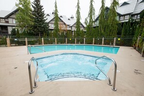 A swimming pool with a hot tub, surrounded by a fence and trees. - Perfect location | Free Parking | Pool & Hot Tub (Whistler)