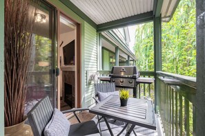 Ein überdachter Außenbereich mit Grill, Sitzgelegenheit und Blick auf Grünflächen.