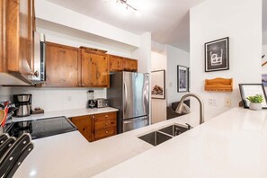 A modern kitchen with wooden cabinets, stainless steel appliances, and a white countertop. - Perfect location | Free Parking | Pool & Hot Tub (Whistler)