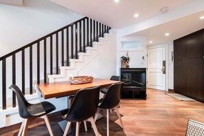 A modern kitchen with a wooden table, black chairs, a fireplace, and a staircase. - Spacious Rustic 1BDR in the Heart of Whistler (Whistler)