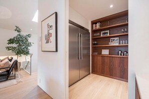 Eine moderne Küche mit integriertem Kühlschrank, Holzböden und einem gerahmten Kunstwerk an der Wand.
