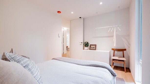 Een moderne slaapkamer met een bed, nachtkastje, stoel en uitzicht.