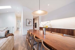 A modern kitchen with a wooden dining table, chairs, a pendant light, and a vase with flowers. - Elegant Chalet | Walk to Blackcomb Gondola | Sauna and Cold plunge (Whistler)