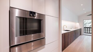 Een moderne keuken met roestvrijstalen apparatuur, een inbouwoven en een groot raam met uitzicht op een besneeuwd landschap.