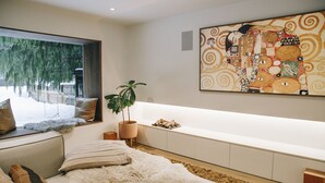 Een moderne slaapkamer met een groot raam, een bank, een bed, een plant en een kunstwerk aan de muur.