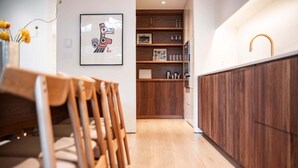 Een moderne keuken met houten kastjes, een eethoek van hout en een lijstwerkkunstwerk aan de muur.
