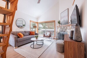 Ein modernes Wohnzimmer mit grauem Sofa, einem runden Couchtisch, einem Holznachttisch und einem Kamin.