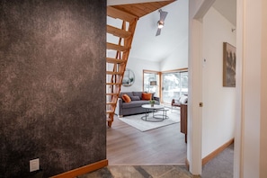 A modern interior with a staircase, a grey sofa, and a round coffee table. - 2+loft | Walk to Creekside Gondola | Pet friendly (Whistler)