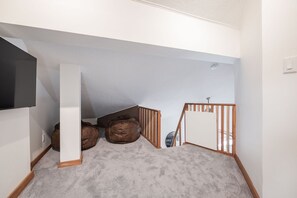 A hallway with a white wall, a wooden railing, and a grey carpet. - 2+loft | Walk to Creekside Gondola | Pet friendly (Whistler)
