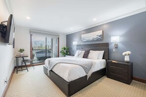 Ein modernes Schlafzimmer mit Bett, Nachttischen, Schreibtisch und Fernseher.