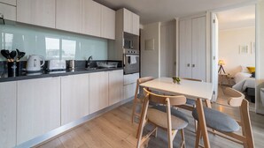 A modern kitchen with wooden cabinets, a black countertop, and a dining area with a white table and wooden chairs. - San Isidro Ideal for Families 4 (Santiago)