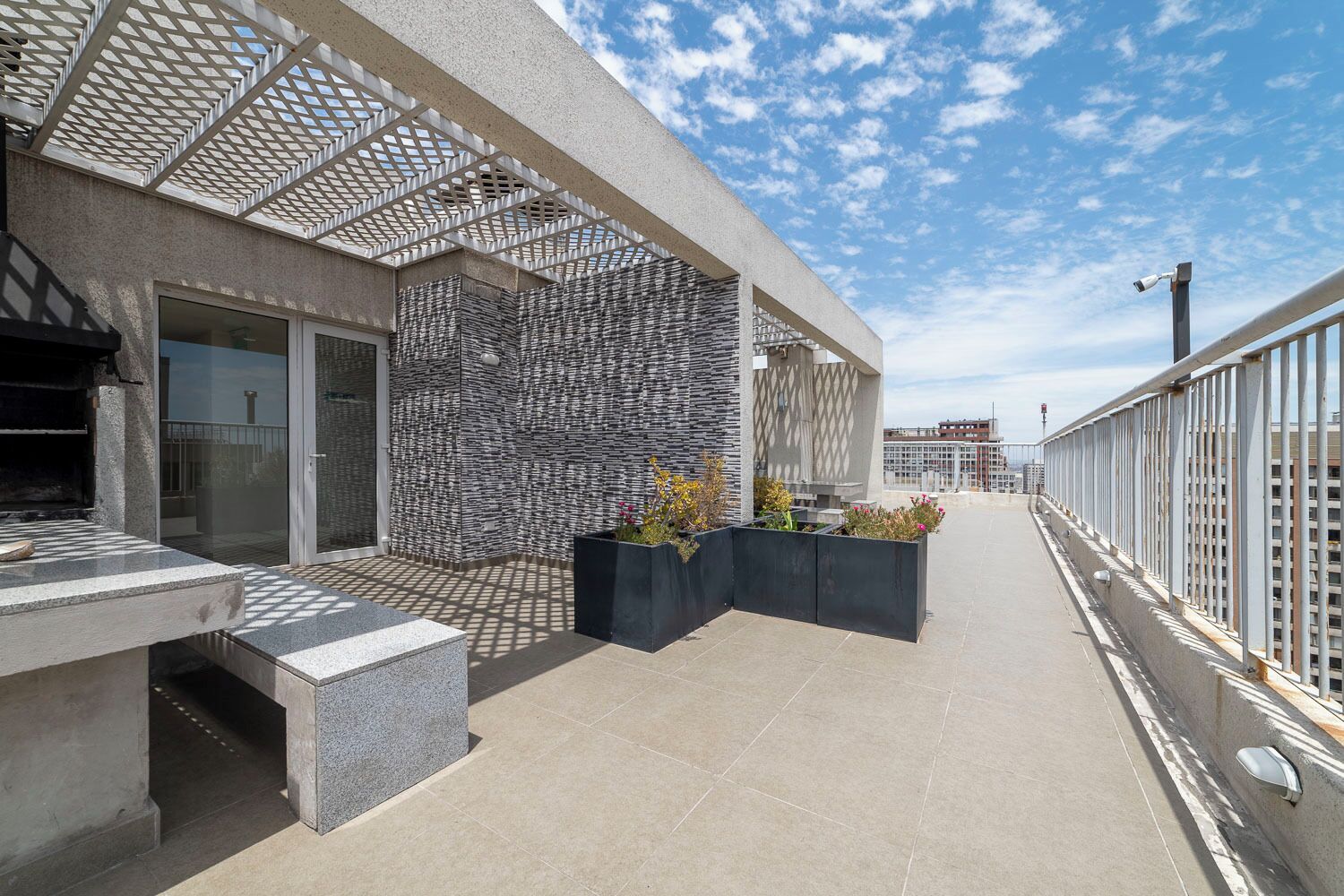 Une terrasse sur le toit, avec un mur en pierre, des sièges extérieurs et une vue sur le panorama urbain.