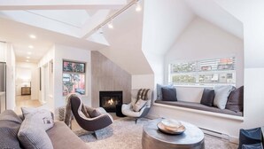 Un salon moderne avec une cheminée, un coin salon et une vue par la fenêtre.
