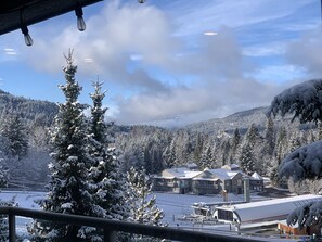 Schneebedeckte Landschaft mit einem Gebäudekomplex und einem mit Schnee beladenen Baum im Vordergrund.