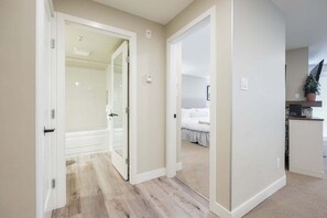 Un pasillo que da a un dormitorio con cama, un baño con ducha y una pequeña cocina.